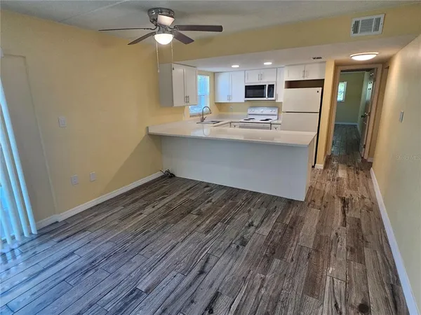 a room with kitchen island a wooden floor and stainless steel appliances