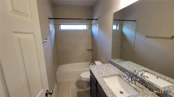 a bathroom with a granite countertop sink a toilet and shower