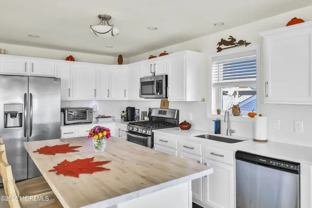 a kitchen with stainless steel appliances granite countertop a sink stove and white cabinets with wooden floor