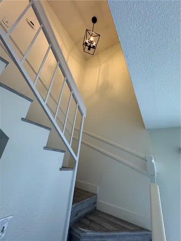 a view of a room with a hanging light and hardwood floor