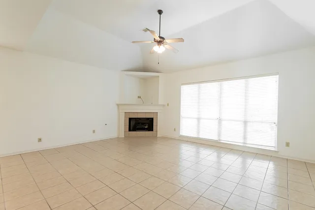 an empty room with chandelier fan and windows