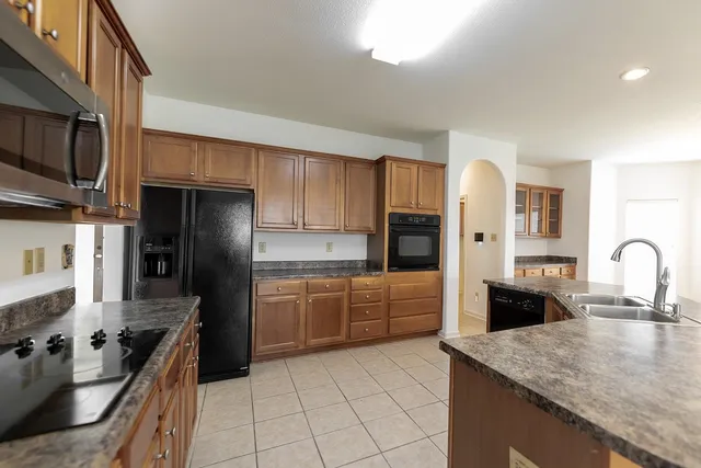 a kitchen with granite countertop a refrigerator stove top oven and sink