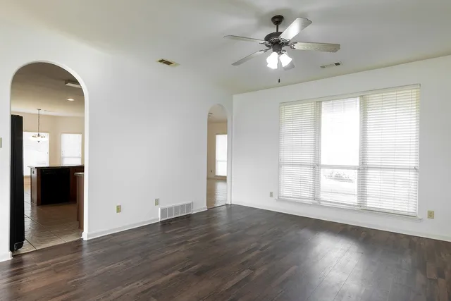 a view of an empty room with wooden floor and a window
