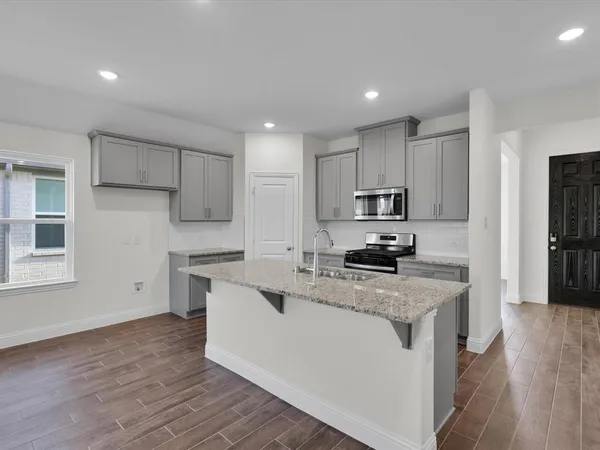 a kitchen with granite countertop a sink stove and refrigerator