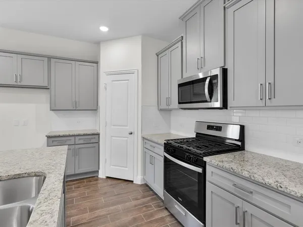 a kitchen with granite countertop cabinets stainless steel appliances and wooden floor