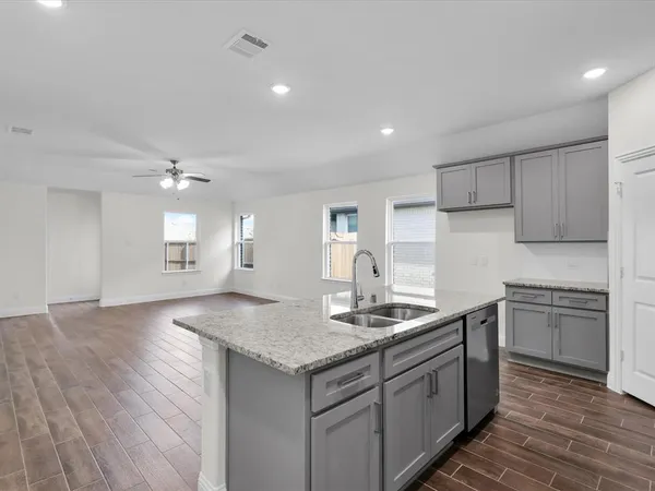 a kitchen with kitchen island granite countertop a sink cabinets and wooden floor