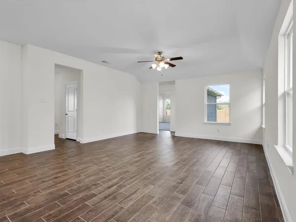 a view of an empty room with a window and wooden floor