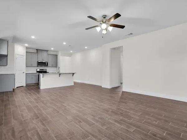 a view of an empty room with kitchen and a window