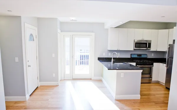 a kitchen with kitchen island granite countertop a stove top oven a sink a counter space and cabinets