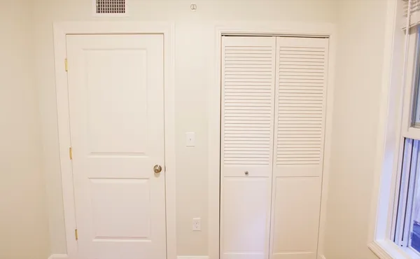 a view of a bedroom with a white cabinet and a window