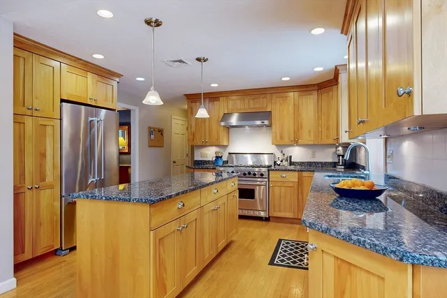 a kitchen with stainless steel appliances granite countertop a sink a stove and a refrigerator