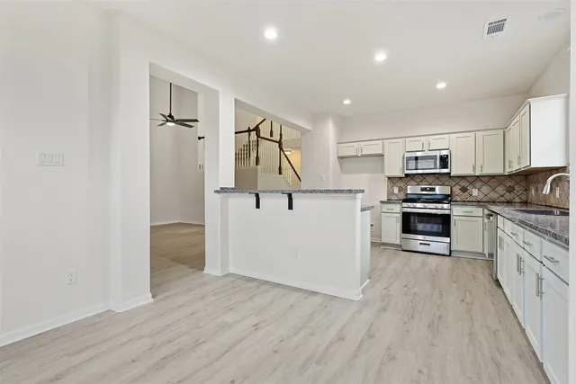 a kitchen with granite countertop a refrigerator and a stove top oven