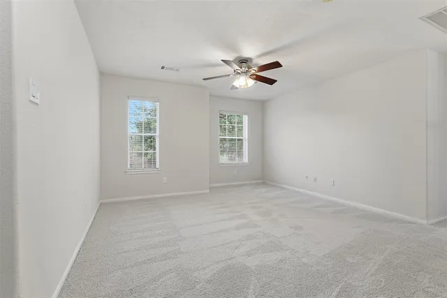 an empty room with windows and fan