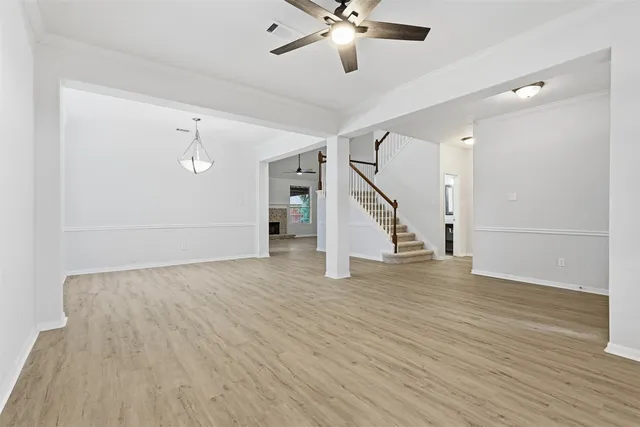 a view of an empty room with wooden floor and staircase