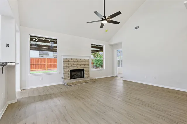an empty room with windows fireplace and fans