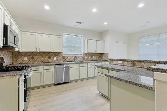a kitchen with granite countertop cabinets stainless steel appliances and a counter space