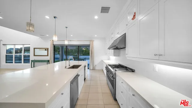 a large kitchen with kitchen island a counter top a stove a sink and a refrigerator