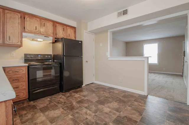 a kitchen with granite countertop a refrigerator and cabinets