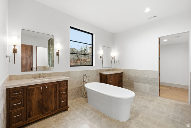 2155 East Wrangler Road Kamas, UT 84036 - Photo 46 of 62 Bathroom featuring two vanities, tile walls, a soaking tub, a wainscoted wall, and recessed lighting