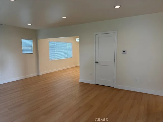 a view of an empty room with wooden floor and closet