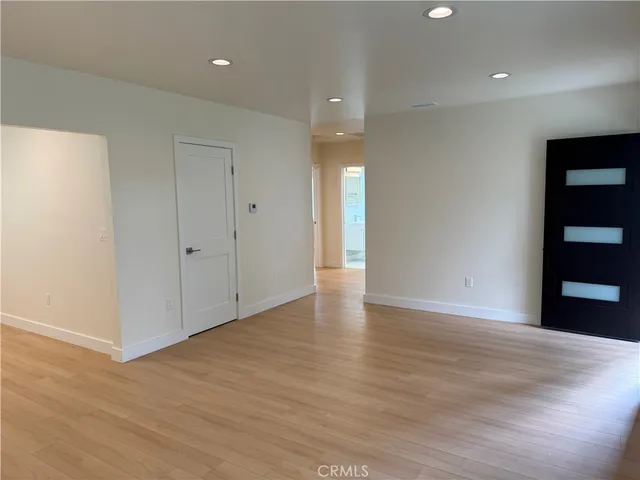 a view of an empty room with wooden floor and closet