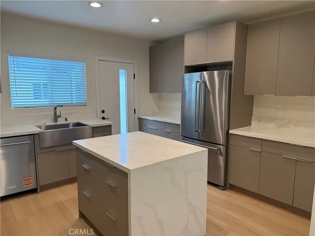 a kitchen that has a sink a refrigerator and a stove top oven