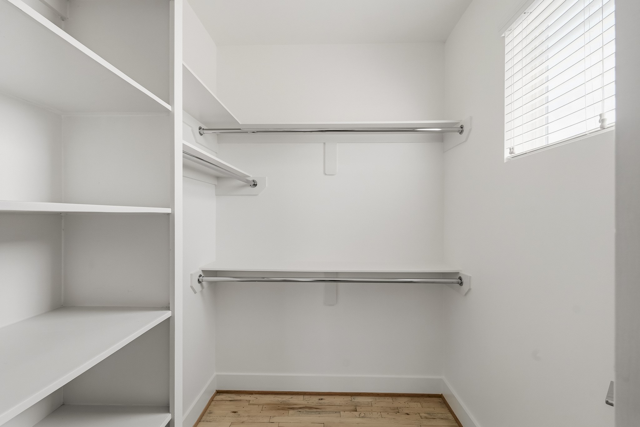 2004 Rosedale Street, Unit D Houston, TX 77004 - Photo 34 of 45 Generously sized walk-in closet has a window with blinds, built-in shelving and multiple hanging rods, offering abundant storage and a beautifully organized space for clothing and accessories.