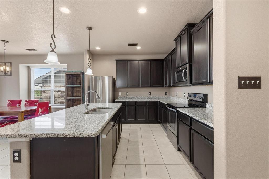 5513 Wharfside Place Denton, TX 76208 - Photo 8 of 37 a kitchen with granite countertop stainless steel appliances and wooden cabinets