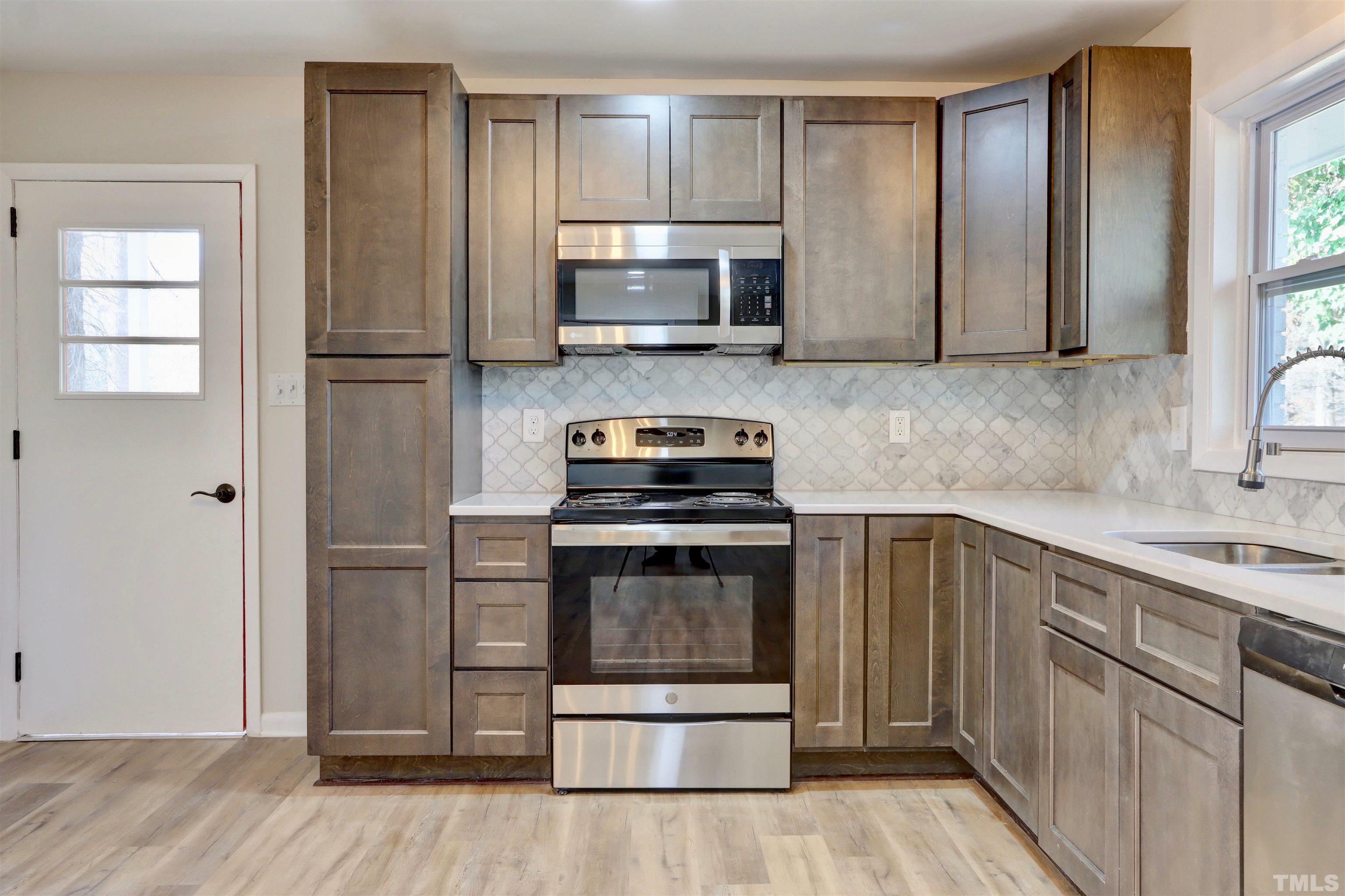 418 Grovemont Road Raleigh, NC 27603 - Photo 8 of 30 a kitchen with granite countertop a refrigerator stove and microwave