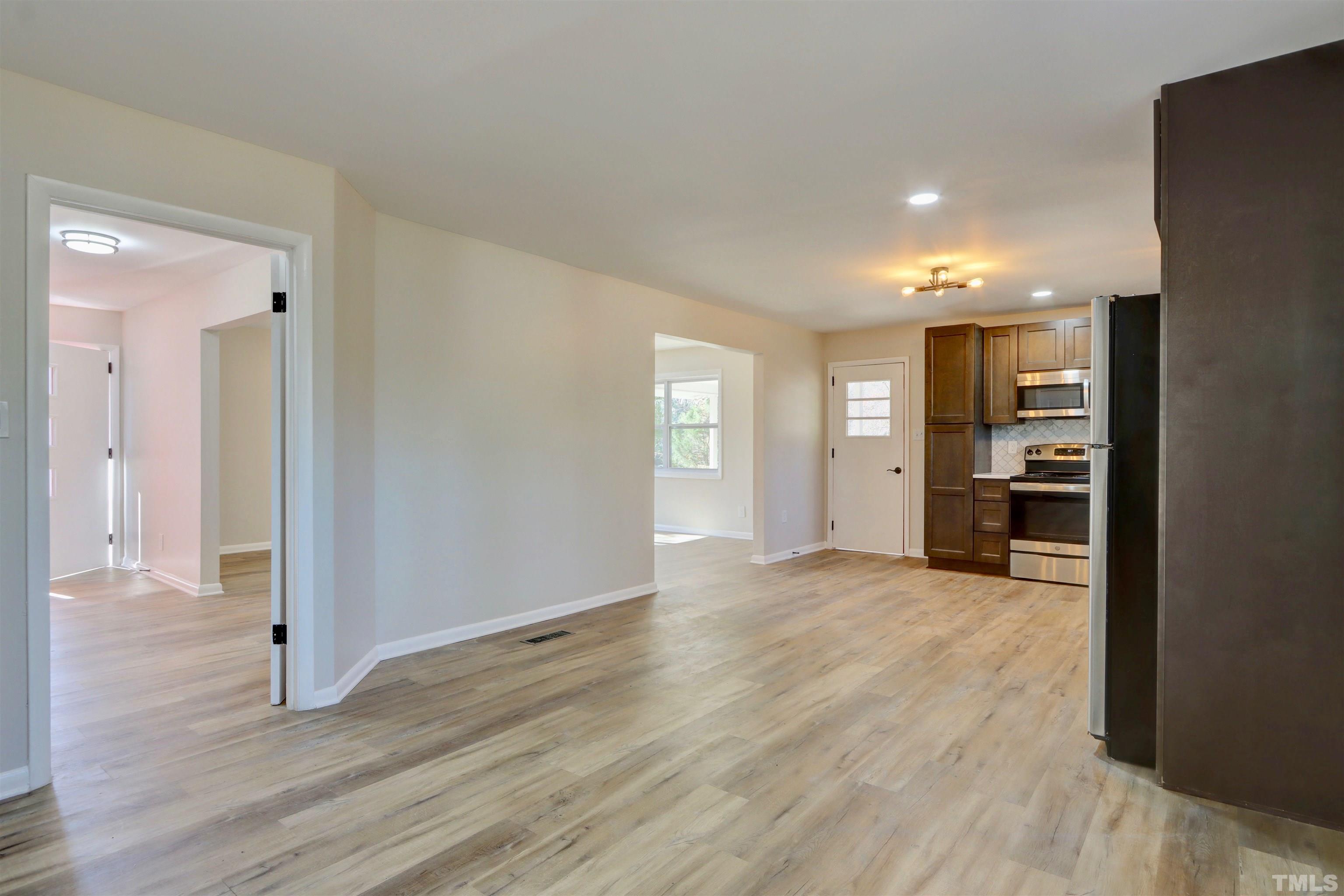 418 Grovemont Road Raleigh, NC 27603 - Photo 10 of 30 a view of an empty room and kitchen with wooden floor