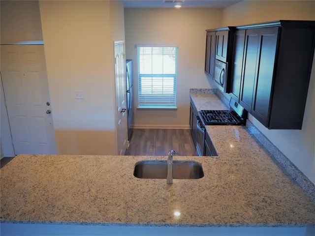 a kitchen with stainless steel appliances granite countertop a sink and a stove top oven with wooden floor