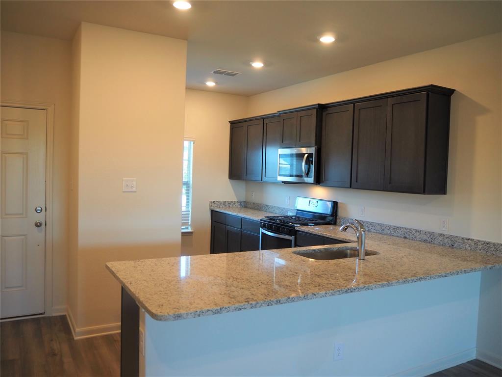 13612 Musselshell Drive Ponder, TX 76259 - Photo 6 of 39 a kitchen with stainless steel appliances granite countertop a sink and a stove top oven with wooden floor