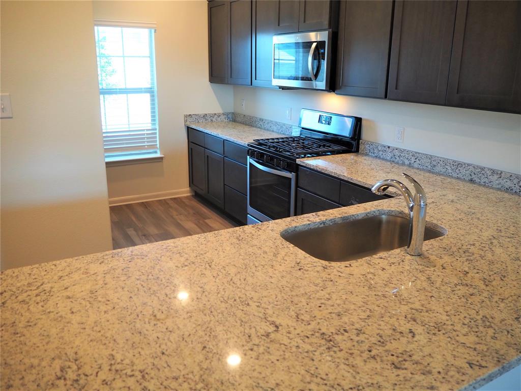 13612 Musselshell Drive Ponder, TX 76259 - Photo 7 of 39 a kitchen with stainless steel appliances a sink a stove a microwave a sink and cabinets