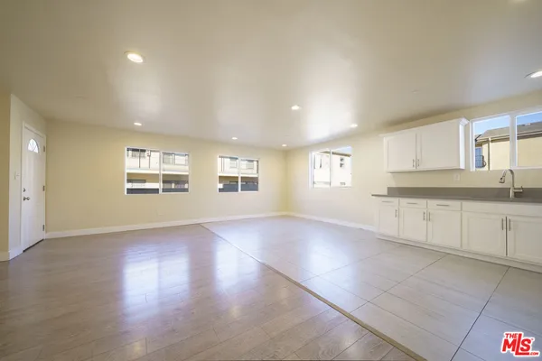 a view of an empty room with a kitchen and a window