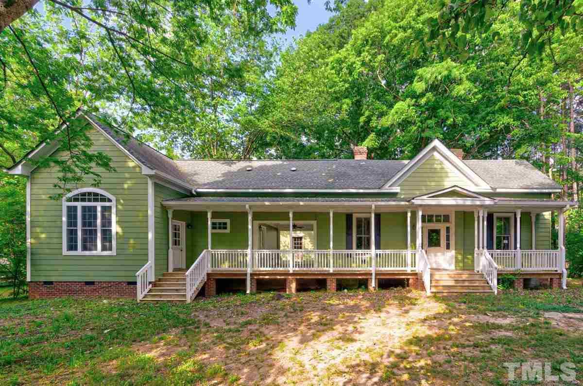 5816 Old Stage Road Raleigh, NC 27603 - Photo 2 of 30 a view of a house with a large window and a yard with plants and large trees