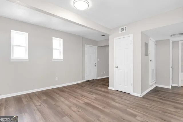 a view of an empty room with wooden floor and a window