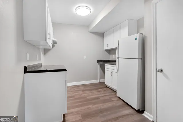 a kitchen with a refrigerator a stove top oven a counter space and wooden floor