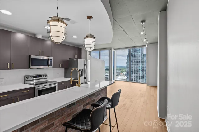 a kitchen with stainless steel appliances a refrigerator a stove a sink dishwasher and a dining table with wooden floor