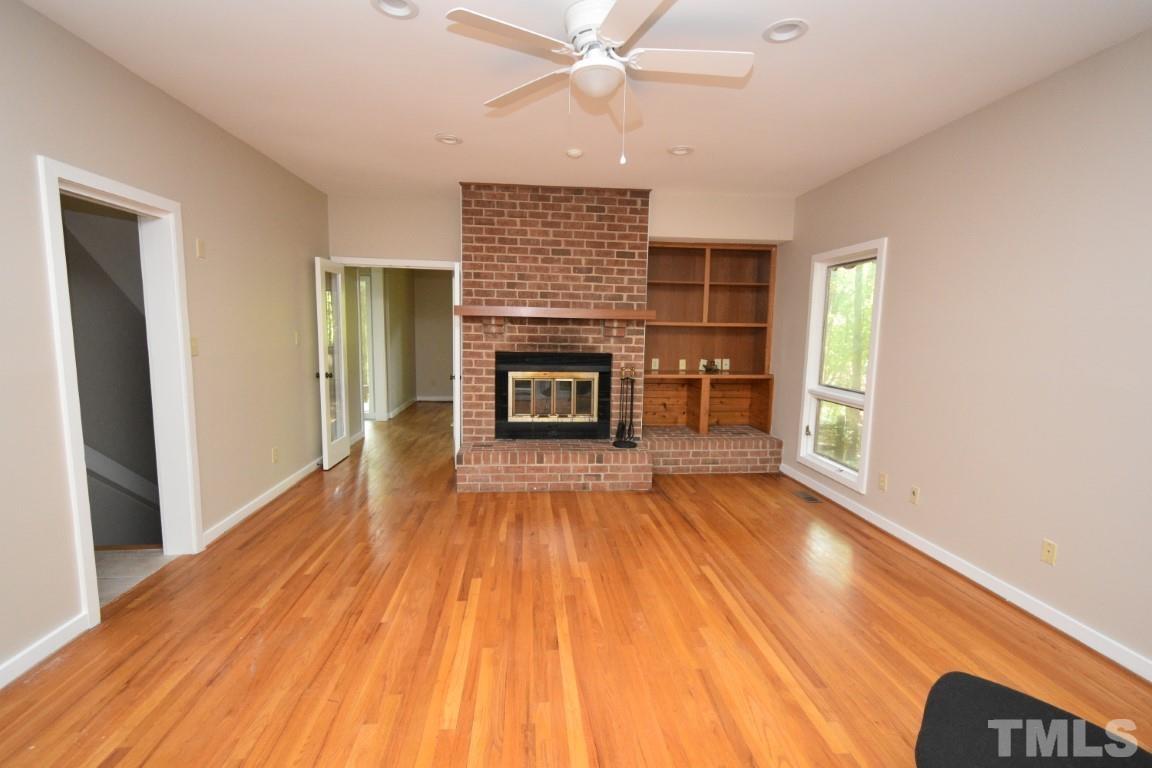 408 Constitution Drive Durham, NC 27705 - Photo 16 of 39 an empty room with wooden floor fireplace and windows