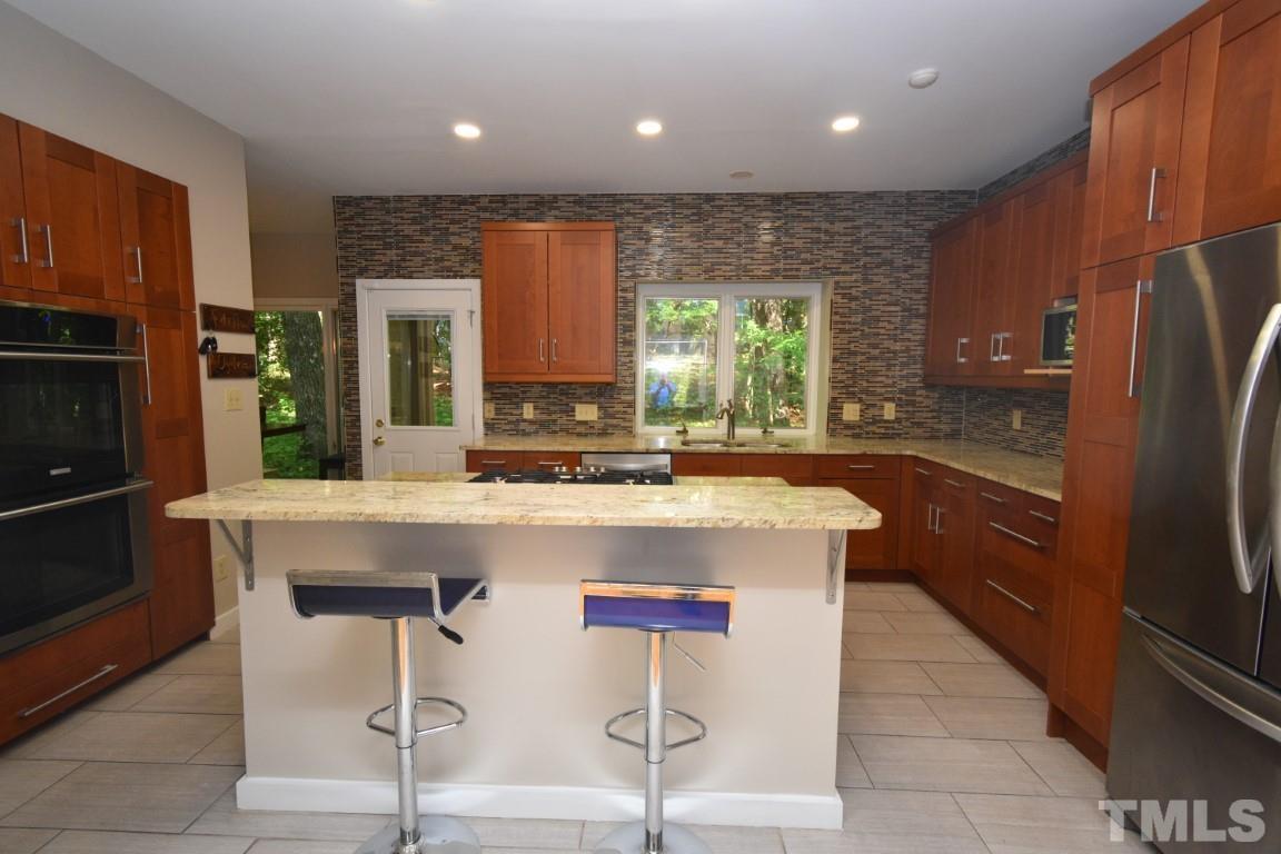 408 Constitution Drive Durham, NC 27705 - Photo 5 of 39 a kitchen with kitchen island granite countertop wooden cabinets and a refrigerator