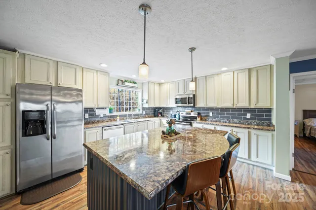 a kitchen with granite countertop a counter space cabinets stainless steel appliances and a view of living room