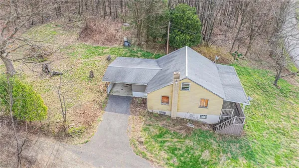 a aerial view of a house next to a yard with large trees