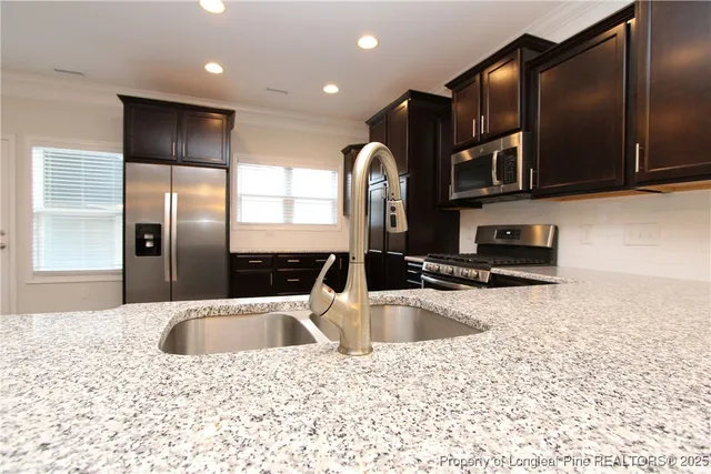 a kitchen with stainless steel appliances granite countertop a sink a refrigerator and a granite counter tops