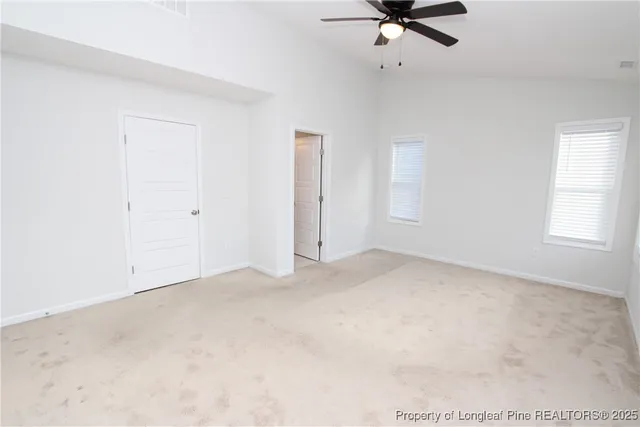 an empty room with a ceiling fan and carpet