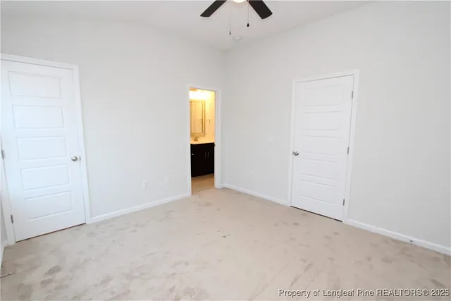 an empty room with a ceiling fan and carpet
