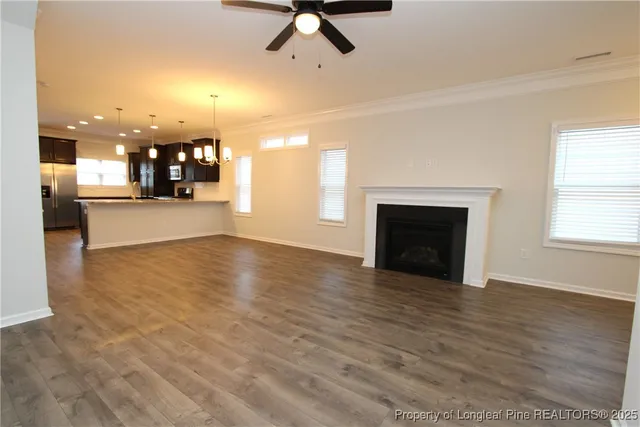 an empty room with wooden floor a fireplace and windows