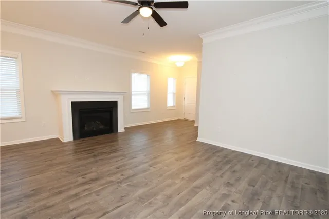 an empty room with wooden floor fireplace and windows