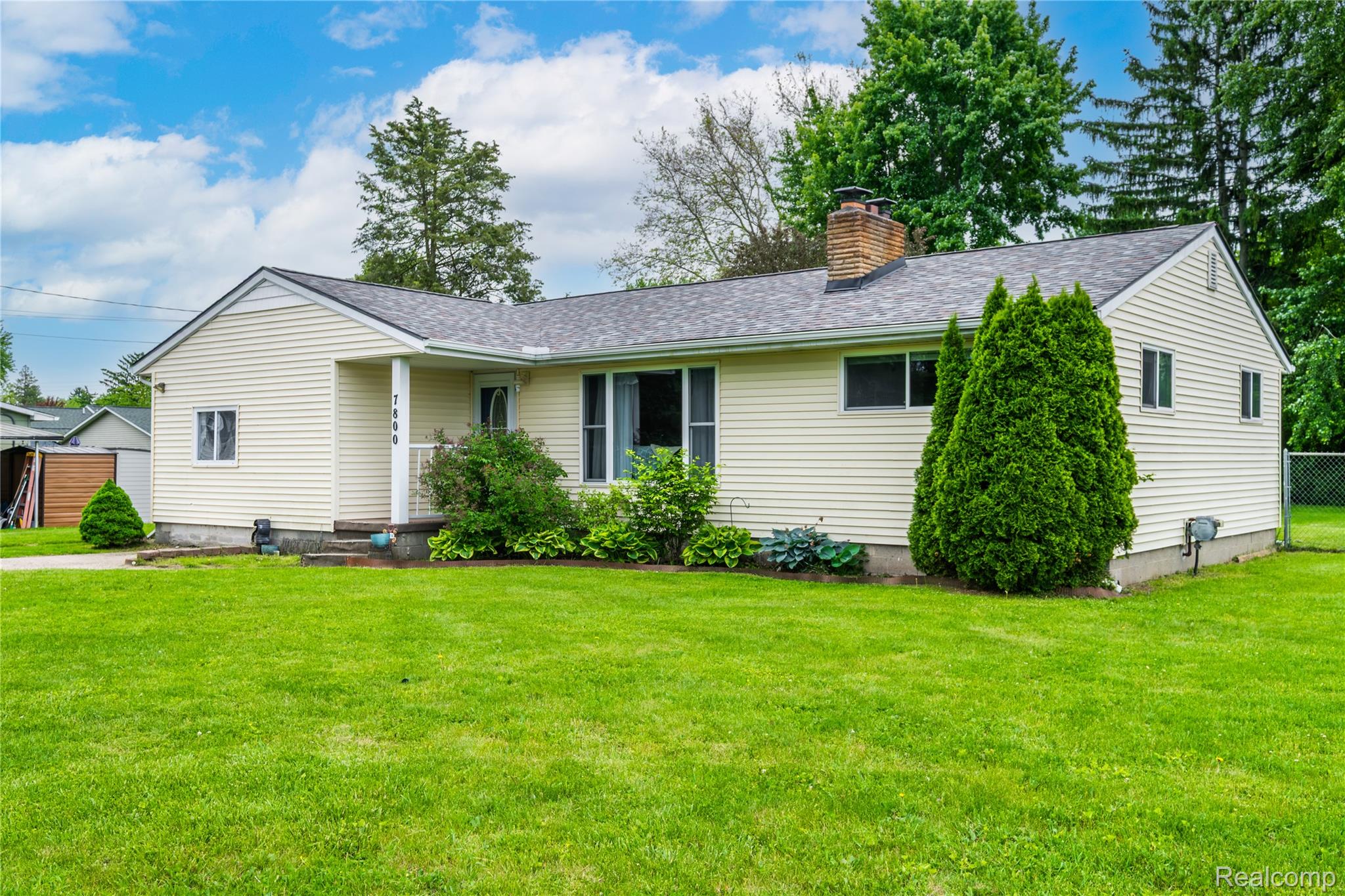 7800 Maple Street Birch Run, MI 48415 - Photo 18 of 29 Ranch-style exterior with light-colored siding, a dark shingle roof, and a prominent brick chimney
