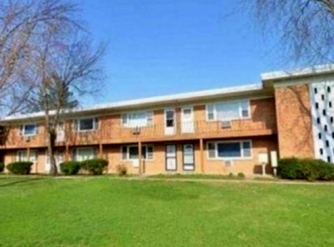 a view of an apartment with a large tree and a big yard
