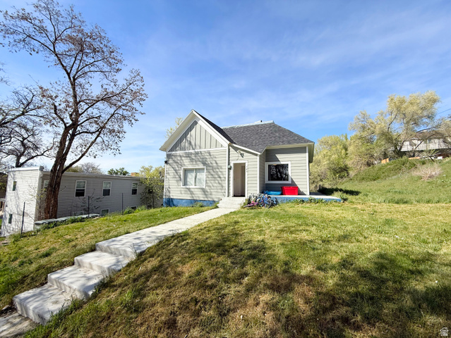 View of front of house featuring board and batten siding, a front yard, and a shingled roof